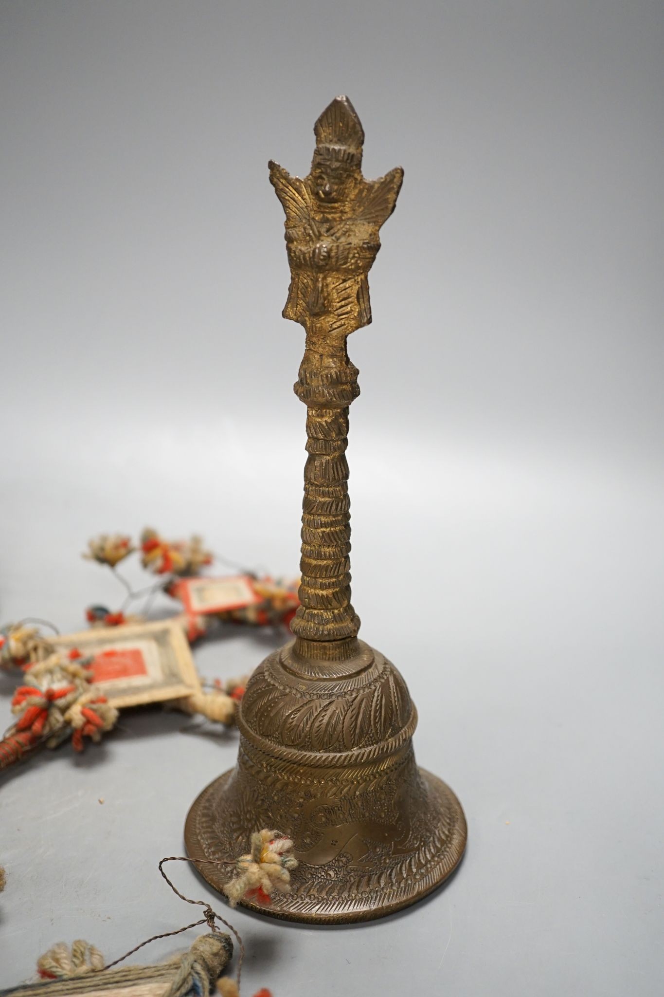 A Himalayan brass bell and bowl, a woolwork finial, 43 cm high, an Islamic tinned metal censer (4)